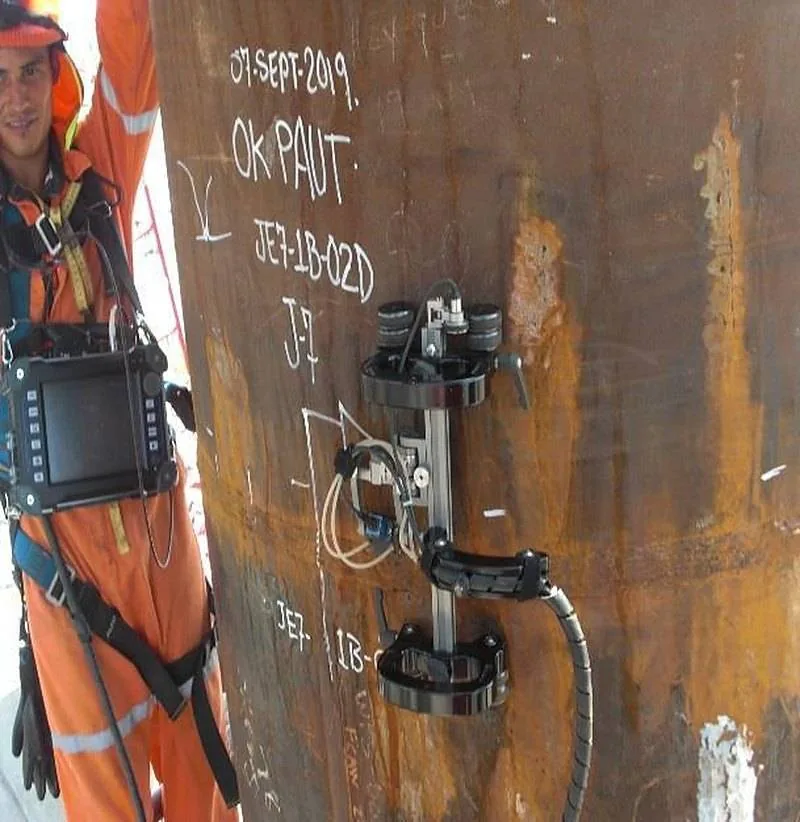 Técnico con el equipo de arreglo de fases y el escáner colocado sobre una soldadura marcada como aprobada